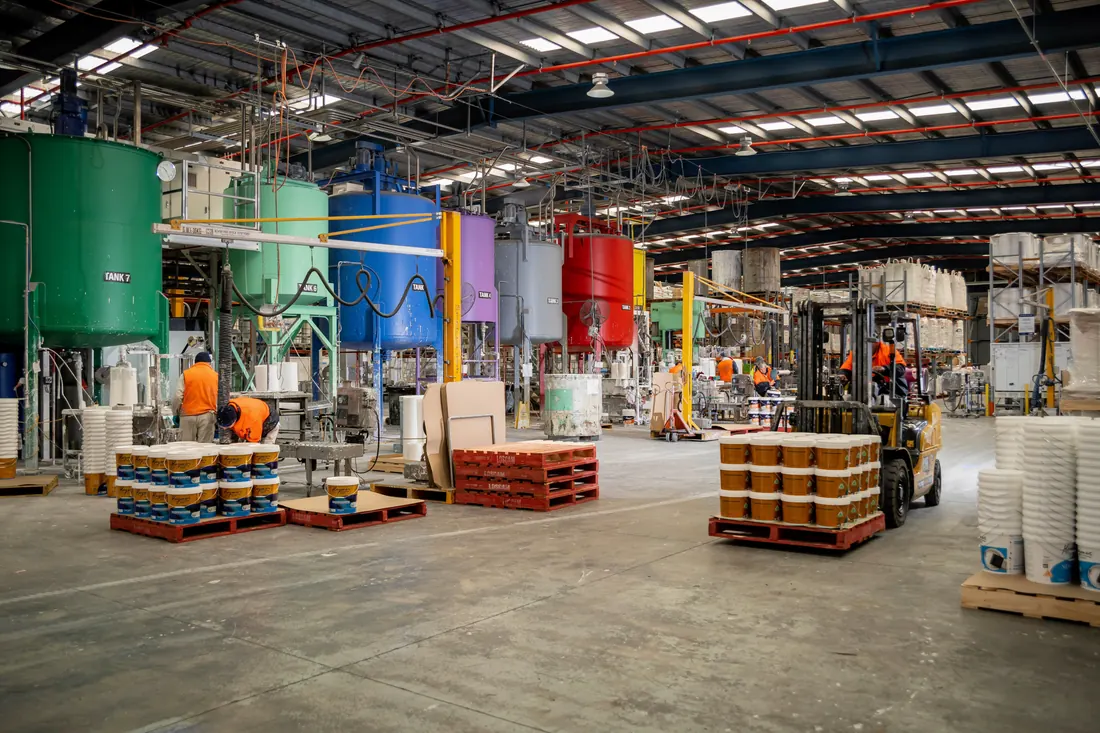 Paint production area with mixing tanks and containers of colored coatings
